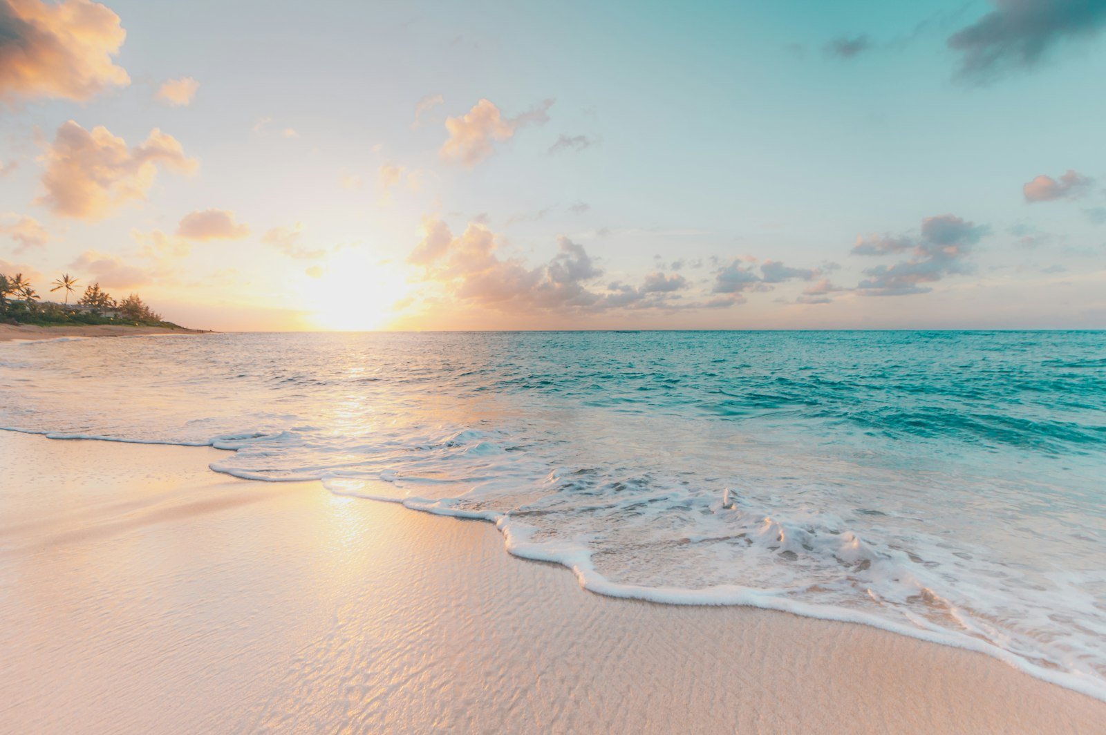 Sunlit shoreline with waves washing onto the sand