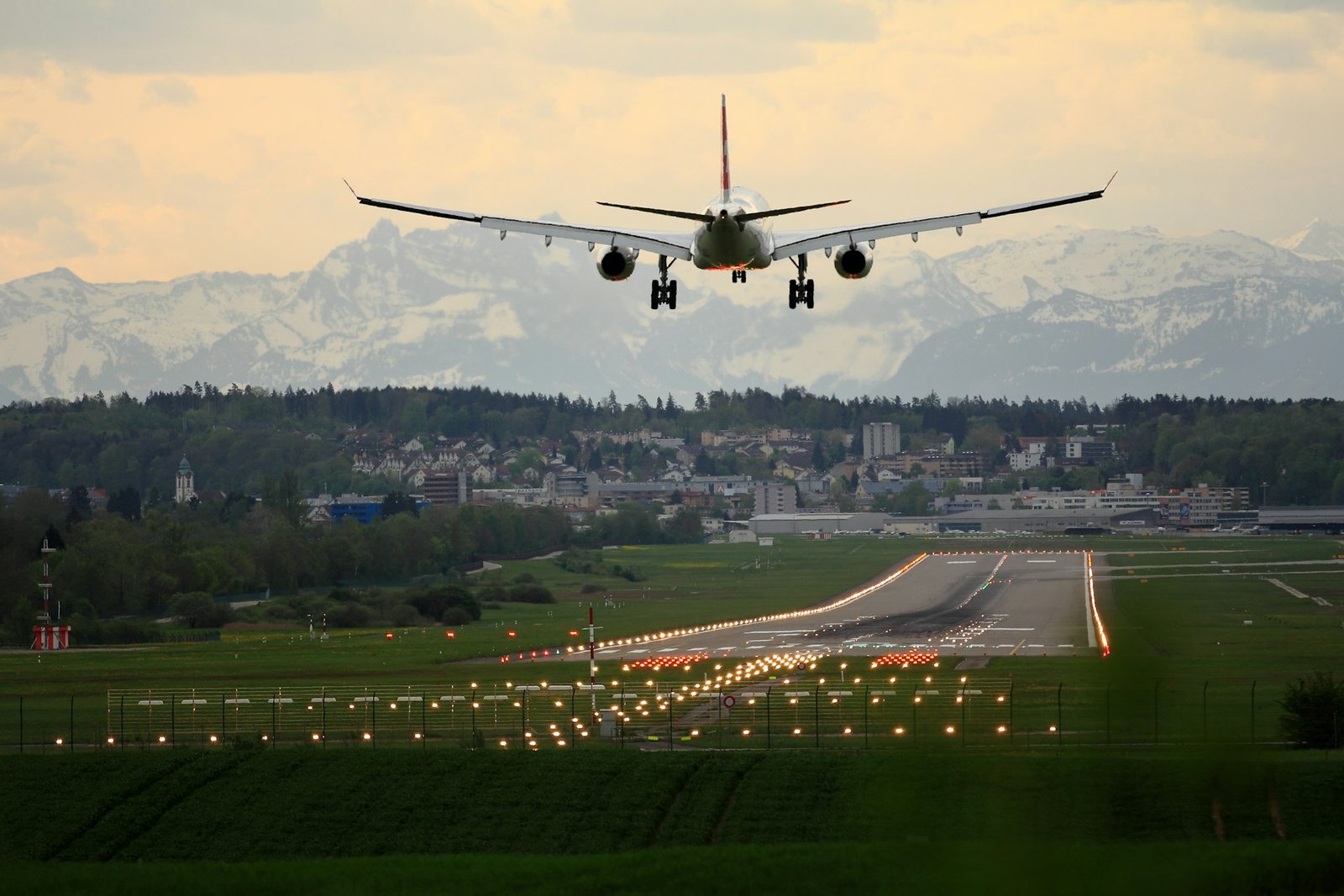 Airplane departing over a runway toward snow-covered mountains
